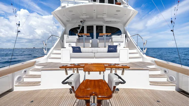 Slide: The Image of Expansive Aft Deck with Fishing Rods The aft deck of the 2017 Viking 92 Enclosed Bridge 'Double Barrel' showcases a spacious fishing and lounging area, complete with a central fighting chair. The teak flooring and dual staircases provide a luxurious touch, while the built-in seating offers c - 8439574