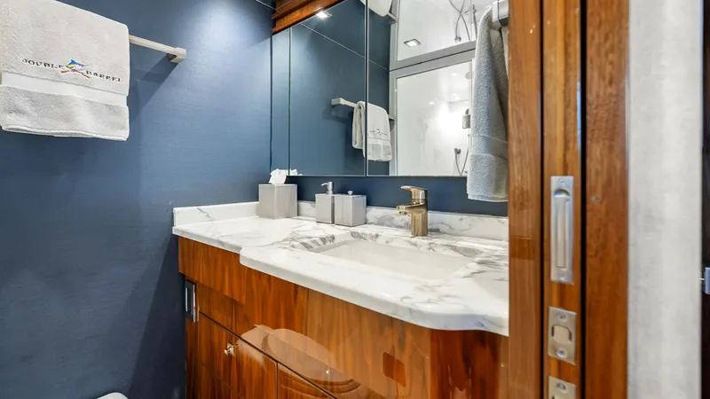 Slide: The Image of Elegant Guest Bathroom Vanity This stylish guest bathroom on the Viking 92 Enclosed Bridge features a luxurious marble countertop and a sleek, polished wood vanity. The space is accented by sophisticated lighting and a large mirror, enhancing the sense of openness. Modern fixtures add - 8439610