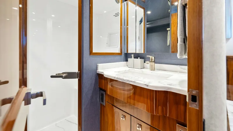 Slide: The Image of Luxurious En-Suite Bathroom View This elegant en-suite bathroom on the 2017 Viking 92 Enclosed Bridge features a sleek marble countertop and high-gloss wood cabinetry, exuding luxury and sophistication. The spacious layout includes a full-sized walk-in shower and ample storage, complemen - 8439605