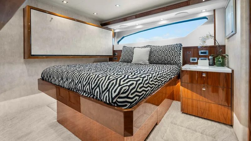 Slide: The Image of Luxurious Guest Stateroom The guest stateroom on the Viking 92 Enclosed Bridge offers a plush, inviting retreat with its stylish bed adorned in a bold patterned cover. Rich wood cabinetry complements the elegant design, while large windows provide ample natural light and stunning - 8439607