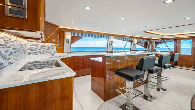 Slide: The Image of Elegant Galley and Bar Area This luxurious galley on the Viking 92 Enclosed Bridge features sleek marble countertops and high-end appliances, perfect for culinary enthusiasts. The polished wood cabinetry adds warmth and elegance, while bar seating provides a casual dining option wit - 8439576