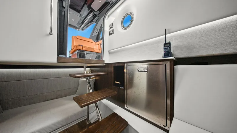 Slide: The Image of Lower Cabin with Compact Galley This stylish lower cabin of the 2022 Cruisers Yachts 34 GLS features a compact galley with a stainless steel refrigerator. The comfortable seating area is upholstered in premium fabrics, complemented by warm wood finishes on the steps and cabinetry. A por - 8398530