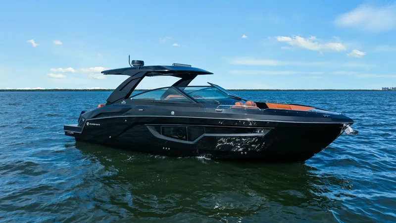Slide: The Image of Portside View of 2022 Cruisers 34 GLS This image showcases the sleek and modern design of the 2022 Cruisers Yachts 34 GLS from the port side. The elegant black hull is complemented by a spacious open cockpit, featuring stylish seating and a streamlined hardtop. The vessel's contemporary lines - 8398553