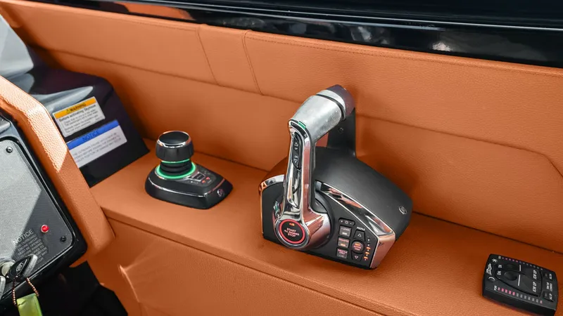 Slide: The Image of Helm Station Controls The helm station of the 2022 Cruisers Yachts 34 GLS features a sleek control panel with a polished throttle and joystick for precise maneuvering. The rich, orange upholstery adds a touch of luxury and sophistication to the helm area. This modern setup ens - 8398521