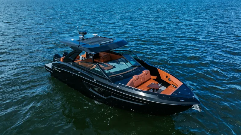 Slide: The Image of Aerial View of Bow and Helm The 2022 Cruisers Yachts 34 GLS showcases its sleek exterior with a striking black hull and vibrant orange seating. The open bow layout invites relaxation with plush seating and a central table, perfect for entertaining. The helm is equipped with advanced - 8398537