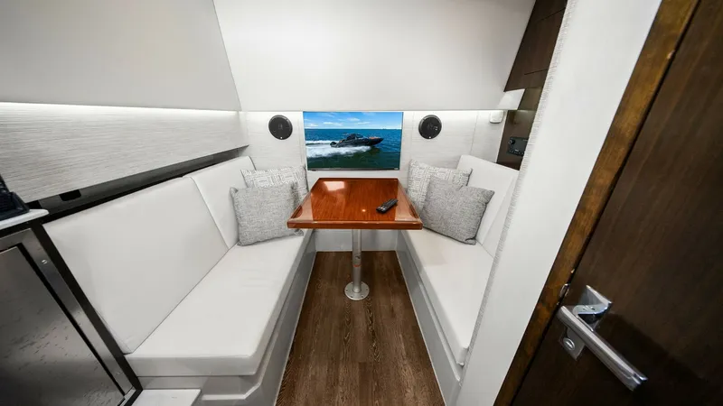 Slide: The Image of Cozy Interior Dinette Area The 2022 Cruisers Yachts 34 GLS features a comfortable interior dinette area with plush seating and elegant wood finishes. The space is designed for relaxation and socializing, offering a sleek wooden table and ample cushions for added comfort. Ambient li - 8398533