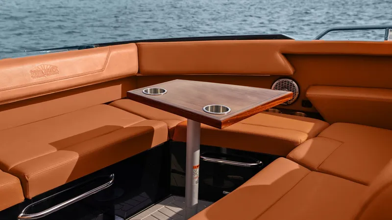 Slide: The Image of Spacious Aft Deck Lounge Area The 2022 Cruisers Yachts 34 GLS features a stylish aft deck lounge with plush, tan leather seating and a sleek wooden table equipped with convenient cup holders. This inviting space is perfect for entertaining guests while enjoying panoramic ocean views. - 8398524