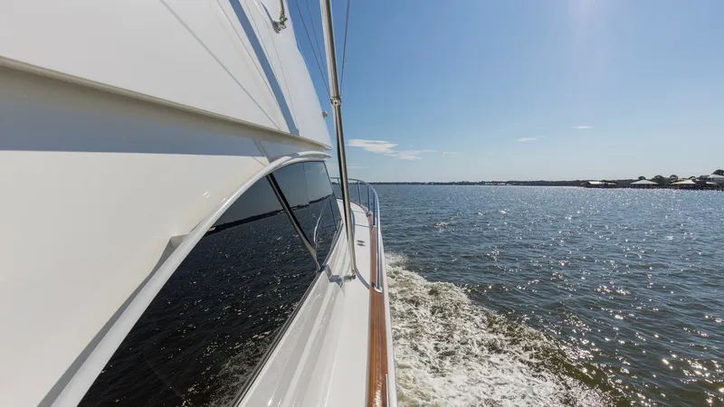 Slide: The Image of Side View with Ocean Horizon The 2024 Viking 54 Convertible, Nomad, is captured cruising through open waters, showcasing its sleek hull design. Sunlight reflects off the polished surfaces, highlighting the vessel's elegant profile and superior craftsmanship. The expansive ocean view - 8439818