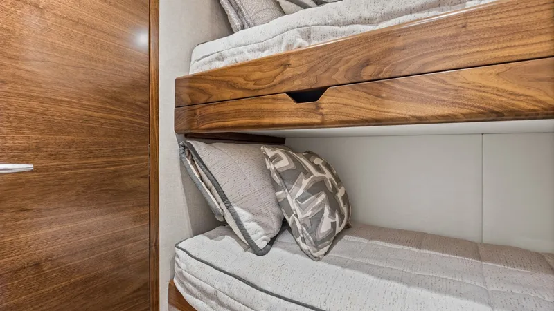 Slide: The Image of Guest Cabin with Bunk Beds This cozy guest cabin on the 2024 Viking 54 Convertible features stylish bunk beds, perfect for accommodating additional guests. The wood finishes add warmth and elegance, while the plush bedding ensures comfort during voyages. The space-efficient design - 8439792