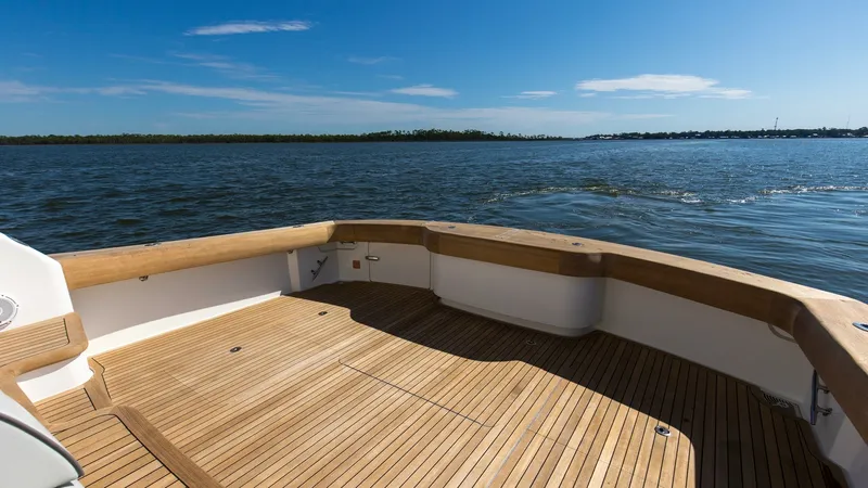 Slide: The Image of Spacious Aft Deck with Teak Flooring The aft deck of the 2024 Viking 54 Convertible, Nomad, showcases a beautifully finished teak floor, offering durability and elegance. The wide-open space is perfect for leisure activities or fishing, framed by sturdy wooden railings that provide safety an - 8439804
