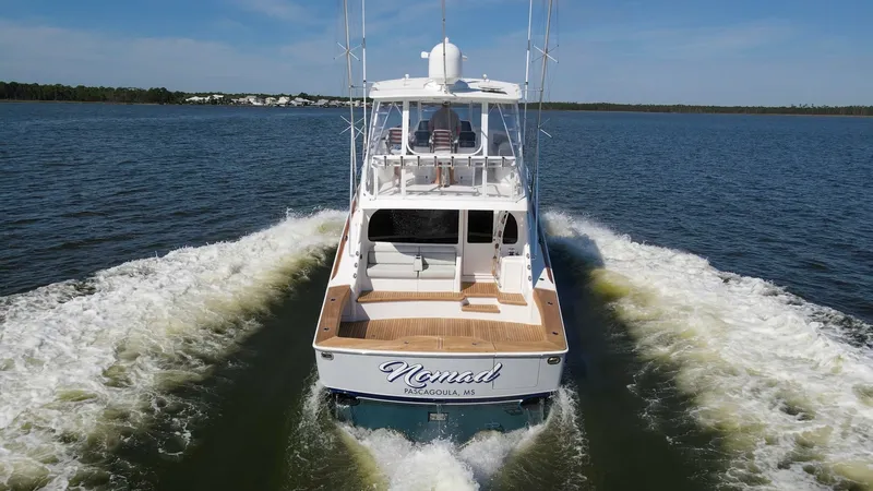 Slide: The Image of Aft View with Open Cockpit The image showcases the aft view of the 2024 Viking 54 Convertible, highlighting its spacious open cockpit. The teak decking adds a touch of elegance, while the ample seating area above ensures comfort during cruising. The vessel's sleek design and powerf - 8439832