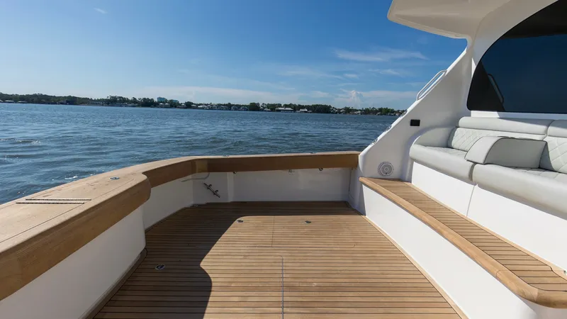 Slide: The Image of Spacious Aft Deck with Seating The Viking 54 Convertible's aft deck offers a generous space with elegant teak flooring, perfect for entertaining or relaxing. The built-in cushioned seating provides comfort while enjoying panoramic views of the water. The clean lines and high-quality ma - 8439806