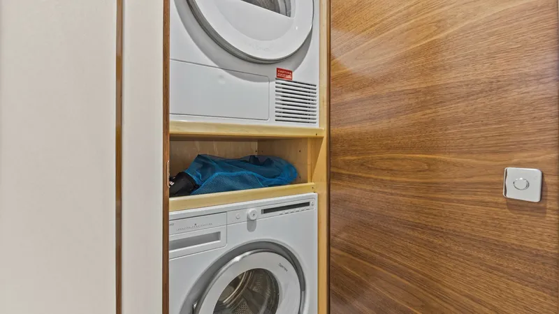 Slide: The Image of Laundry Area with Washer/Dryer The 2024 Viking 54 Convertible features a compact yet efficient laundry area, equipped with a stacked washer and dryer. The sleek cabinetry and modern appliances offer convenience and functionality, making laundry tasks effortless during extended voyages. - 8439786