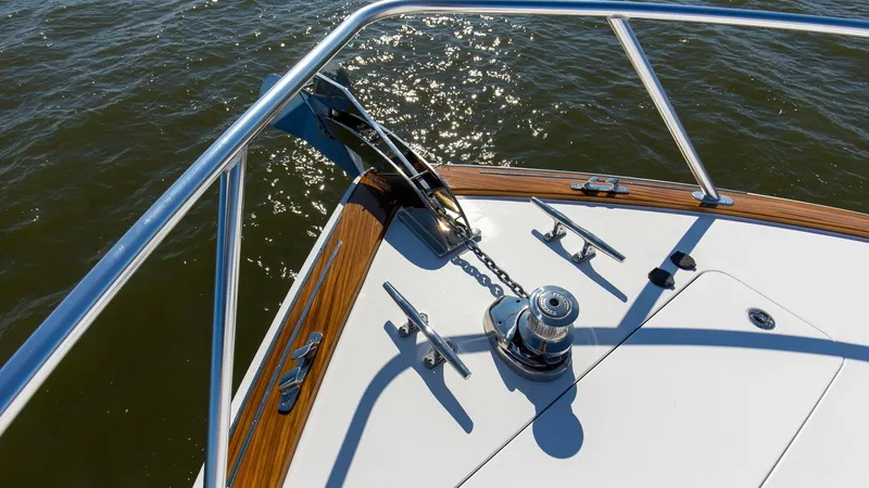 Slide: The Image of Foredeck with Anchor Windlass The foredeck of the 2024 Viking 54 Convertible 'Nomad' features a sleek anchor windlass, accentuated by polished stainless steel fittings. The area is framed by elegant wood trim, offering a touch of luxury against the pristine white deck. This setup ensu - 8439816