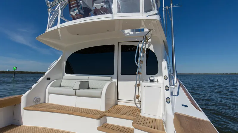Slide: The Image of Aft Deck with Seating and Ladder This image showcases the elegant aft deck of the 2024 Viking 54 Convertible, featuring comfortable built-in seating perfect for relaxation. The teak decking adds a touch of luxury and durability, while the stainless steel ladder provides easy access to th - 8439812