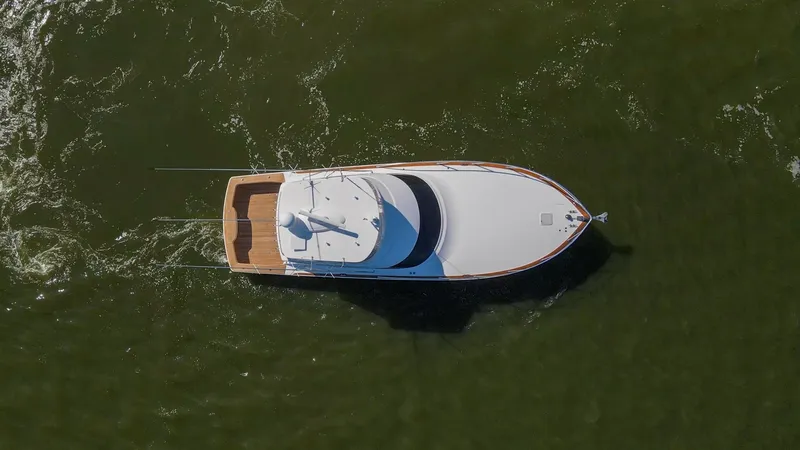 Slide: The Image of Aerial View of Flybridge and Bow This aerial shot showcases the sleek design of the 2024 Viking 54 Convertible's flybridge and bow. The vessel's clean lines and spacious teak aft deck are highlighted against the dynamic backdrop of open water. The streamlined silhouette exemplifies moder - 8439840