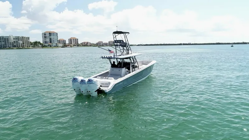 Slide: The Image of Aft View with Triple Outboards This image showcases the aft section of the 2020 Nor-Tech 390 Sport, highlighting its three powerful outboard engines. The vessel's sleek design and sturdy T-top provide an ideal combination of style and functionality. The expansive deck space is perfect - 8521467