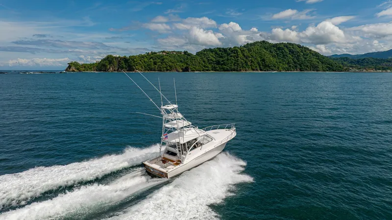 Slide: The Image of Aerial View of Cabo 40 Express Cruising The 2020 Cabo 40 Express 'Knot Working' is captured cruising through serene waters, showcasing its sleek design and powerful performance. The vessel's spacious aft deck and distinctive tower are visible, ideal for sport fishing and leisure. Its wake cutti - 8511618