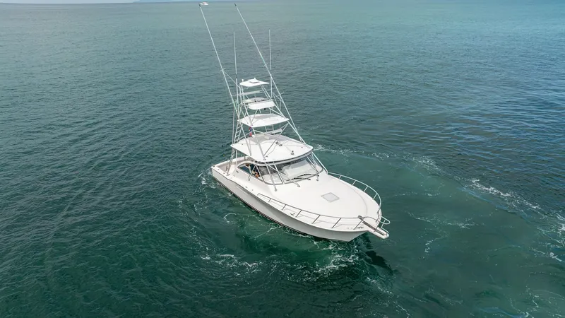 Slide: The Image of Aerial View of Bow and Flybridge This stunning aerial shot showcases the sleek bow and spacious flybridge of the 2020 Cabo 40 Express. The vessel, named 'Knot Working,' cuts through the water with grace, highlighted by its streamlined design and robust fishing tower. The expansive forede - 8511608
