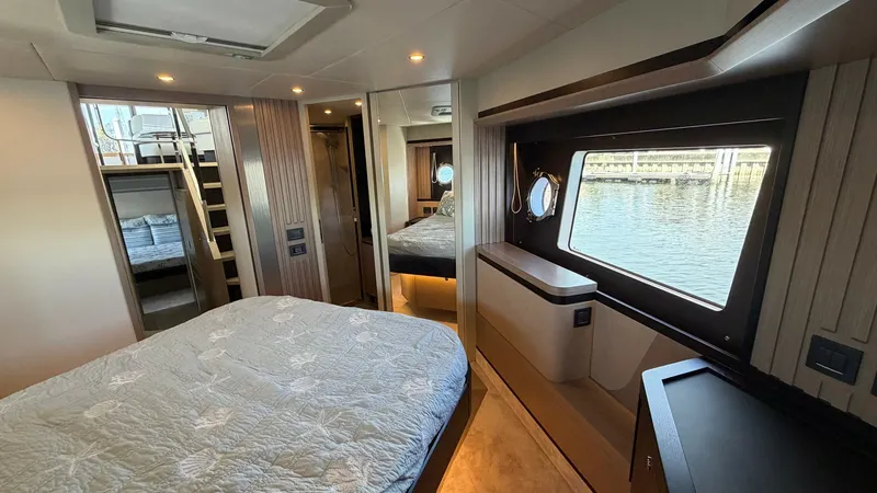 Slide: The Image of Master Stateroom with Large Window The master stateroom of the Absolute Navetta 58 offers a spacious layout with a luxurious double bed. This well-appointed room features elegant wood finishes and ample natural light from the expansive window, providing stunning views of the surrounding wa - 8640125