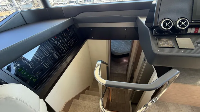 Slide: The Image of Helm Station with Staircase Access This image showcases the helm station of the Absolute Navetta 58, featuring a sleek control panel with advanced navigation equipment. The polished metal handrails lead down to the interior cabins, providing a seamless transition from the helm to the livin - 8640123