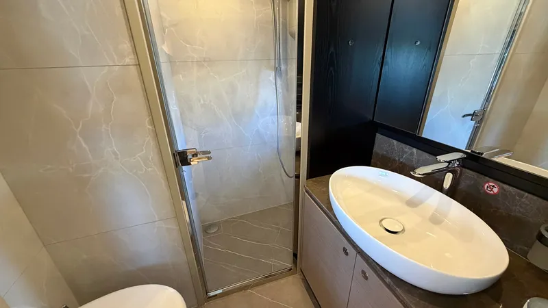 Slide: The Image of Elegant En-Suite Bathroom This en-suite bathroom on the Absolute Navetta 58 showcases a modern design with a sleek glass-enclosed shower and stylish black cabinetry. The vessel sink sits atop a polished surface, adding to the luxurious feel. The use of neutral tones and high-quali - 8640126