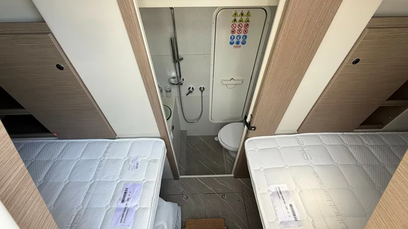 Slide: The Image of Twin Cabin with Ensuite Access This cozy twin cabin on the Absolute Navetta 58 features two comfortable berths with direct access to a compact ensuite bathroom. The light wood finishes and neutral tones create a bright and welcoming atmosphere, while cleverly integrated storage maximiz - 8640155