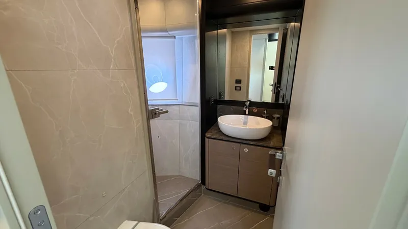 Slide: The Image of Elegant Ensuite Bathroom This stylish ensuite bathroom on the Navetta 58 exudes modern elegance with its sleek marble finishes and contemporary fixtures. The compact space is thoughtfully designed, featuring a spacious shower with glass doors, a chic vessel sink, and ample storag - 8640127