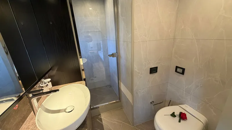 Slide: The Image of Elegant Bathroom with Modern Fixtures This luxurious bathroom on the Absolute Navetta 58 features sleek, modern fixtures and a sophisticated design. The spacious shower area is enclosed with glass, complementing the elegant ceramic basin and contemporary faucet. Marble-look tiling adds a touc - 8640131