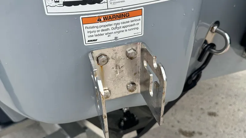 Slide: The Image of Transom Bracket Detail View This image shows the detail of a robust transom bracket on the 2023 SeaVee 270Z. The stainless steel hardware ensures durability and reliability in marine conditions. The visible warning label emphasizes safety precautions, making it clear that this vesse - 8398130