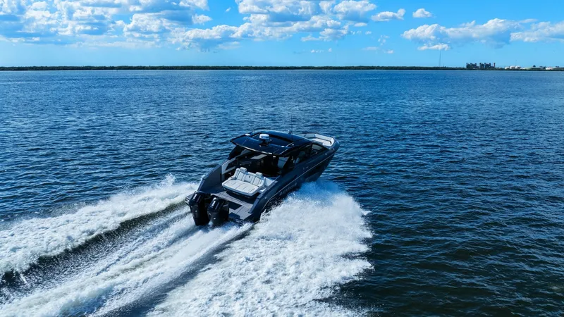 Slide: The Image of Aerial View of Cruisers Yachts 42 GLS This dynamic aerial shot captures the sleek Cruisers Yachts 42 GLS cutting through open waters. The vessel's powerful dual engines create a striking wake, highlighting its impressive speed and agility. With a spacious aft deck for relaxation, this model c - 8619178