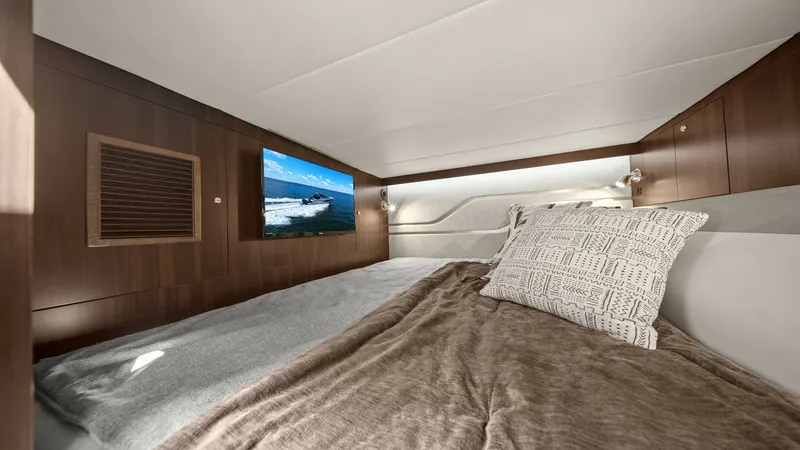 Slide: The Image of Cozy Lower Berth with TV This inviting lower berth on the 2023 Cruisers Yachts 42 GLS offers a comfortable space featuring a plush bed with luxurious linens. The warm wood finishes and soft lighting create a relaxing ambiance, complemented by an integrated flat-screen TV for ente - 8619150