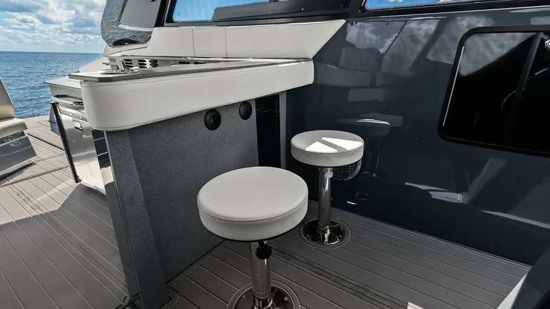 Slide: The Image of Cockpit Bar and Seating Area This image showcases the sleek cockpit bar area of the 2023 Cruisers Yachts 42 GLS. Featuring a modern bar counter with integrated appliances, it is perfect for entertaining. The stylish bar stools offer comfortable seating, complemented by expansive ocea - 8619134