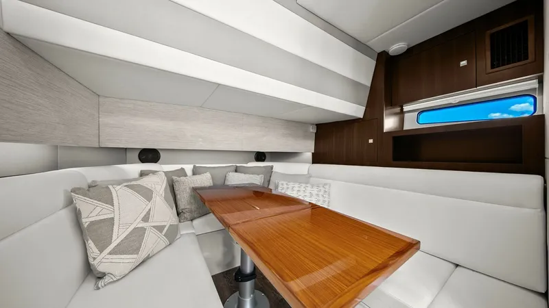 Slide: The Image of Elegant Salon with Convertible Seating The salon of the 2023 Cruisers Yachts 42 GLS features plush white seating arranged around a sleek wooden table, creating a welcoming and luxurious space for relaxation. The contemporary design includes stylish throw pillows and ample natural light, enhanc - 8619154
