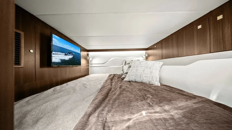 Slide: The Image of Cozy Cabin with Entertainment System This inviting cabin on the 2023 Cruisers Yachts 42 GLS offers a plush sleeping area adorned with soft bedding and elegant wood paneling. The space is enhanced by a wall-mounted TV, perfect for relaxation and entertainment on the water. Ambient lighting an - 8619151