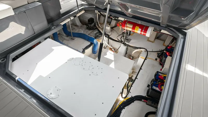 Slide: The Image of Engine Compartment with Systems Access This image showcases the spacious engine compartment of the 2023 Cruisers Yachts 42 GLS, featuring well-organized systems and easy access for maintenance. The area is equipped with essential components, including wiring, a fire extinguisher system, and ba - 8619163
