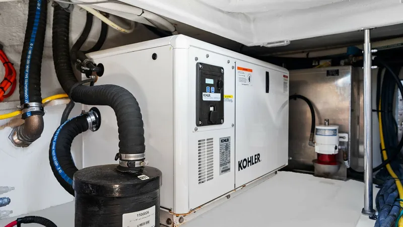 Slide: The Image of Engine Room with Kohler Generator This image showcases the well-organized engine room of the 2023 Cruisers Yachts 42 GLS, featuring a Kohler generator. The space is efficiently arranged, with clearly visible piping and wiring, ensuring easy maintenance and accessibility. The clean design - 8619164