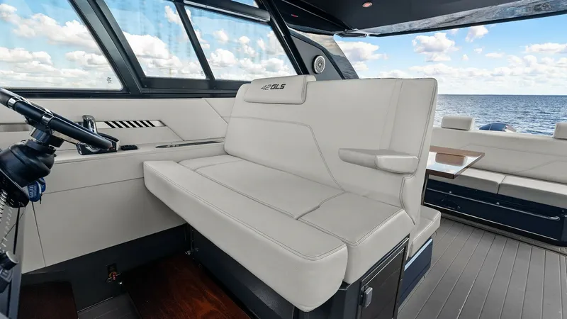 Slide: The Image of Helm Seating and Cockpit View This image showcases the helm seating area of the 2023 Cruisers Yachts 42 GLS, featuring plush, cream-colored upholstery for maximum comfort. The expansive windows provide stunning panoramic views, enhancing the open and airy feel of the cockpit. The mode - 8619139