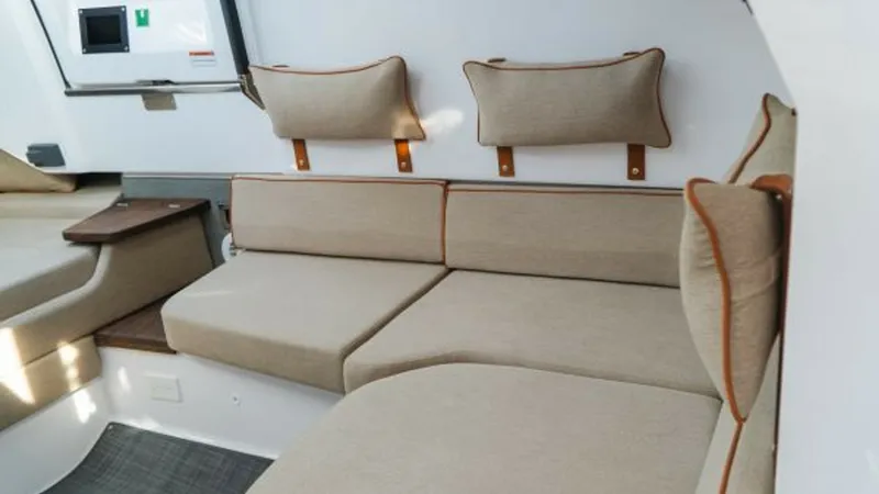 Slide: The Image of Cozy Aft Cabin Seating Area This inviting aft cabin on the 2022 Axopar 37 Barbus features plush, upholstered seating with stylish piping, providing a comfortable retreat for relaxation. The neutral color palette and clean lines contribute to a modern, sophisticated ambiance. Thought - 8439362