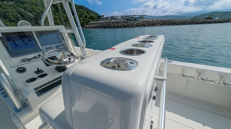 Slide: The Image of Helm Console with Rod Holders The helm console of the 2013 SeaVee 32, 'Poco Mas,' features a sleek design with a modern steering system and integrated electronics. The console is equipped with multiple stainless steel rod holders, ideal for avid anglers. The surrounding open deck prov - 8738099