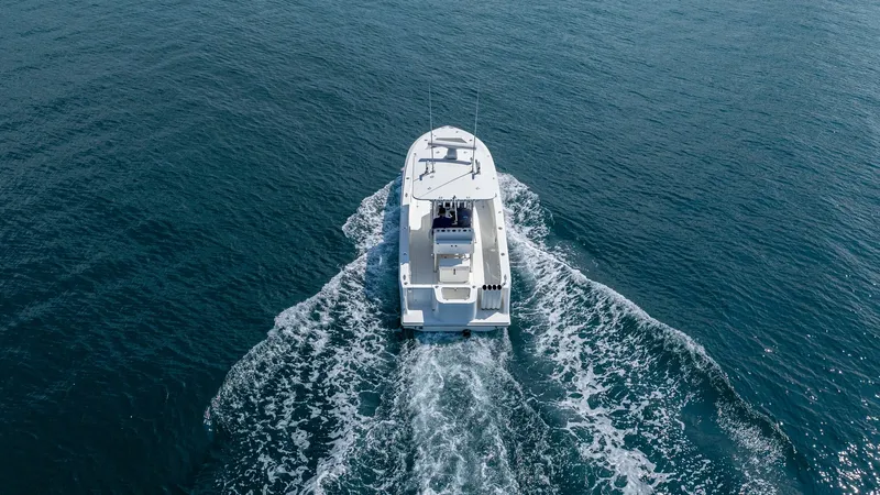 Slide: The Image of Aerial Stern View in Motion This aerial shot captures the 2013 SeaVee 32 model, 'Poco Mas,' cruising gracefully through open waters. The vessel's sleek design and powerful performance are evident as it cuts through the waves, leaving a striking wake behind. The spacious aft deck off - 8738118