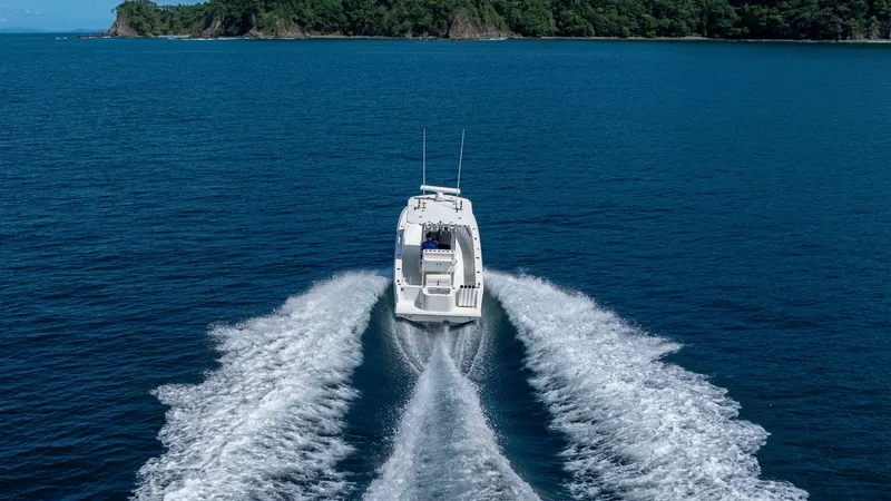 Slide: The Image of Aerial View of Aft Deck in Motion Captured in stunning detail, the SeaVee 32 'Poco Mas' demonstrates its powerful performance as it cuts through the open water. The image showcases the sleek aft deck, highlighting its spacious design and efficient layout. Surrounded by pristine blue water - 8738116