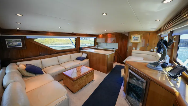 Slide: The Image of Spacious Salon with Entertainment Features The salon of the 2001 Hatteras 60 Convertible offers a luxurious and inviting space, featuring plush cream leather seating arranged around a polished wooden coffee table. Large windows provide ample natural light and picturesque views, enhancing the open - 8734328