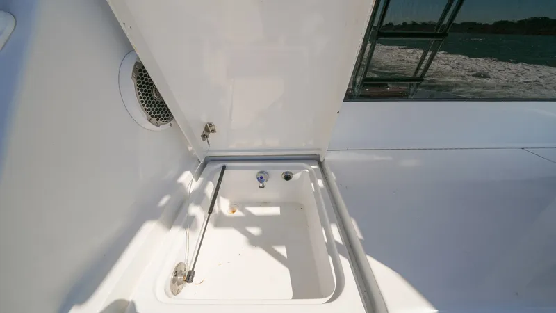 Slide: The Image of Cockpit Fish Box with Lid Open The image showcases the spacious fish box located in the cockpit of the 2001 Hatteras 60 Convertible. The lid is open, revealing a clean and functional storage area ideal for storing freshly caught fish. The surrounding area features a durable, non-slip s - 8734352
