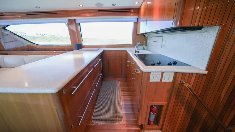 Slide: The Image of Galley with Modern Amenities The galley of the 2001 Hatteras 60 Convertible 'Uno Mas' features sleek wooden cabinetry and ample countertop space, perfect for meal preparation. Equipped with a modern stovetop and sink, this space also benefits from large windows that provide natural l - 8734332