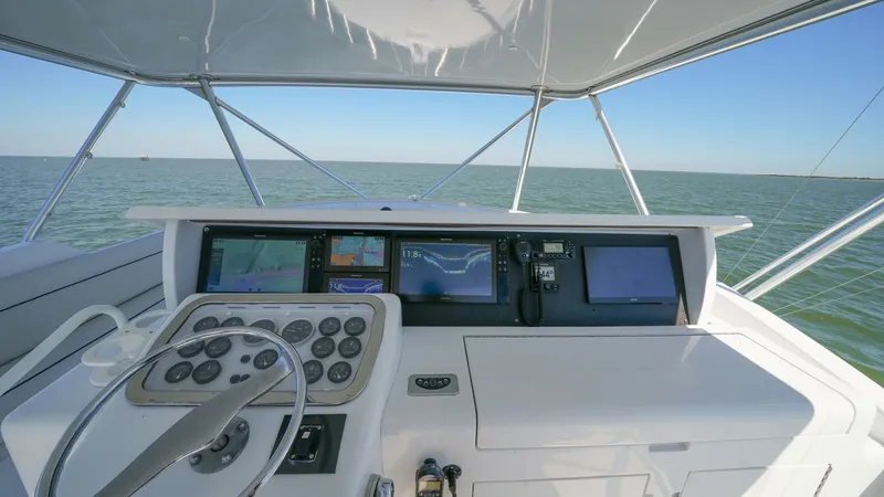 Slide: The Image of Flybridge Helm Station This image showcases the flybridge helm station of the 2001 Hatteras 60 Convertible. The helm is equipped with advanced navigation displays, providing comprehensive control and clear visibility for the captain. The open-air design offers an expansive view - 8734358