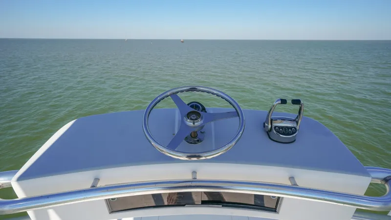 Slide: The Image of Flybridge Helm Station View This image showcases the helm station on the flybridge of the 2001 Hatteras 60 Convertible, Uno Mas. Featuring a sleek steering wheel and modern throttle controls, it offers a commanding view of the open water. The minimalist design ensures easy navigatio - 8734365