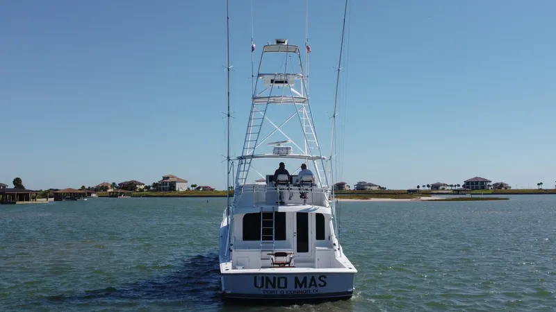 Slide: The Image of Aft View with Tower and Cockpit This image showcases the aft view of the 2001 Hatteras 60 Convertible, 'Uno Mas'. The vessel features a spacious cockpit, ideal for sportfishing, accompanied by a prominent tuna tower offering excellent visibility. The clean lines and sturdy build reflect - 8734377