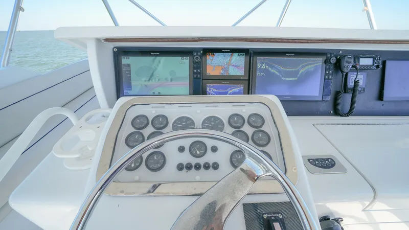 Slide: The Image of Helm Station with Navigation Displays The helm station of the 2001 Hatteras 60 Convertible features a comprehensive array of navigation displays and controls, providing the captain with all necessary tools for smooth sailing. The modern dashboard includes multiple screens for radar, GPS, and - 8734360