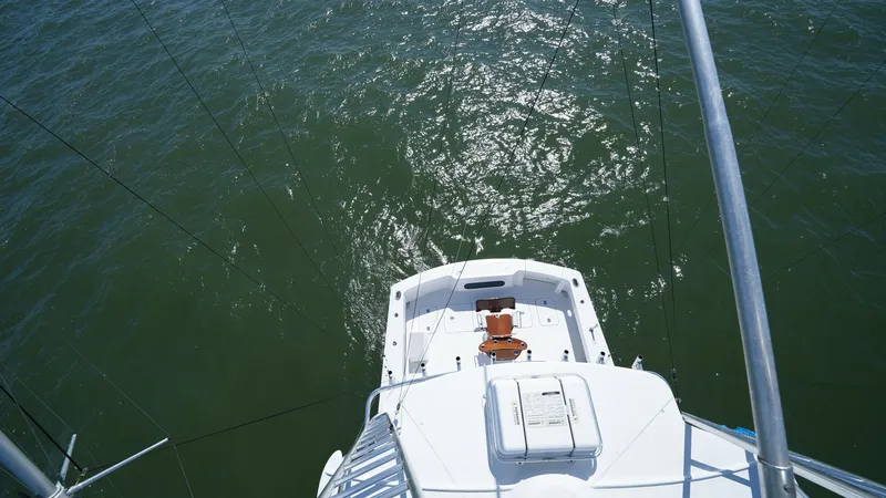Slide: The Image of Flybridge View Over Cockpit This image captures a bird's-eye view from the flybridge of the 2001 Hatteras 60 Convertible, Uno Mas. The cockpit below is spacious, offering ample room for fishing or entertaining, with a central fighting chair as its focal point. The surrounding waters - 8734367